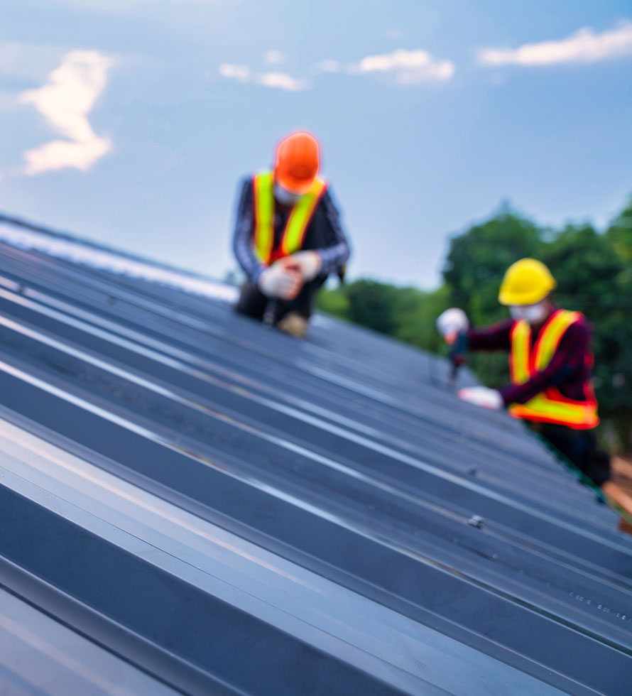 two roofers working on metal roof