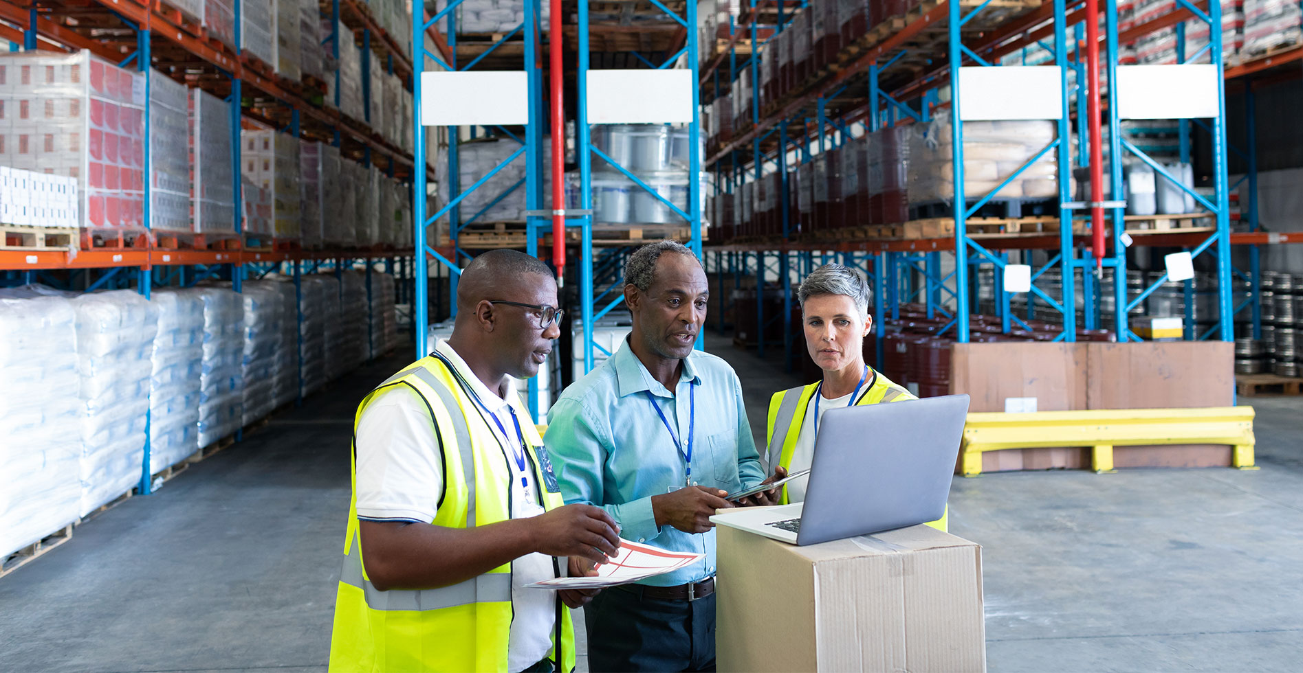 three warehouse workers are on a laptop looking at screen