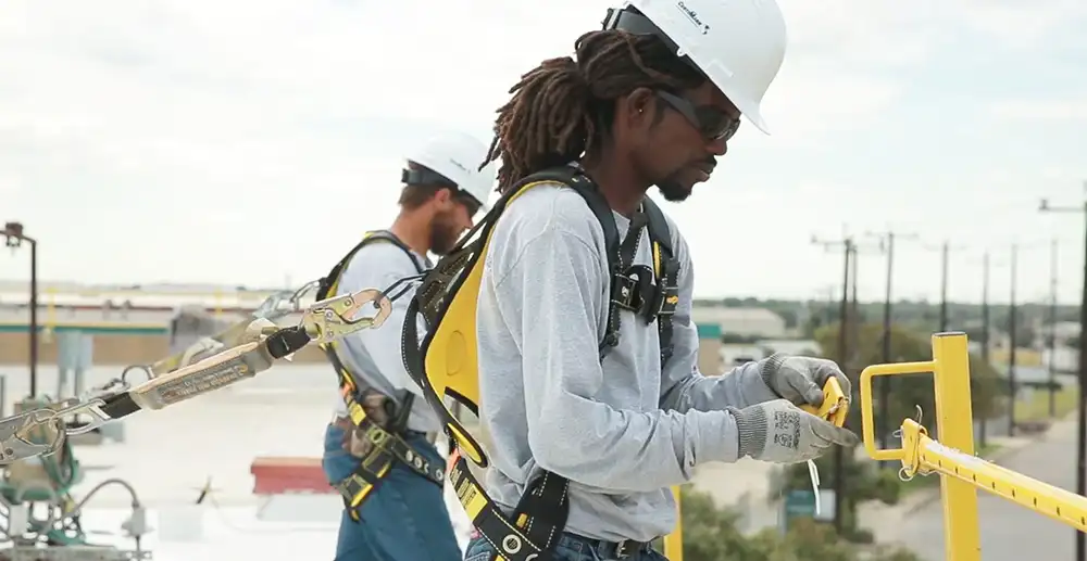 two commercial roofers in full gear at work